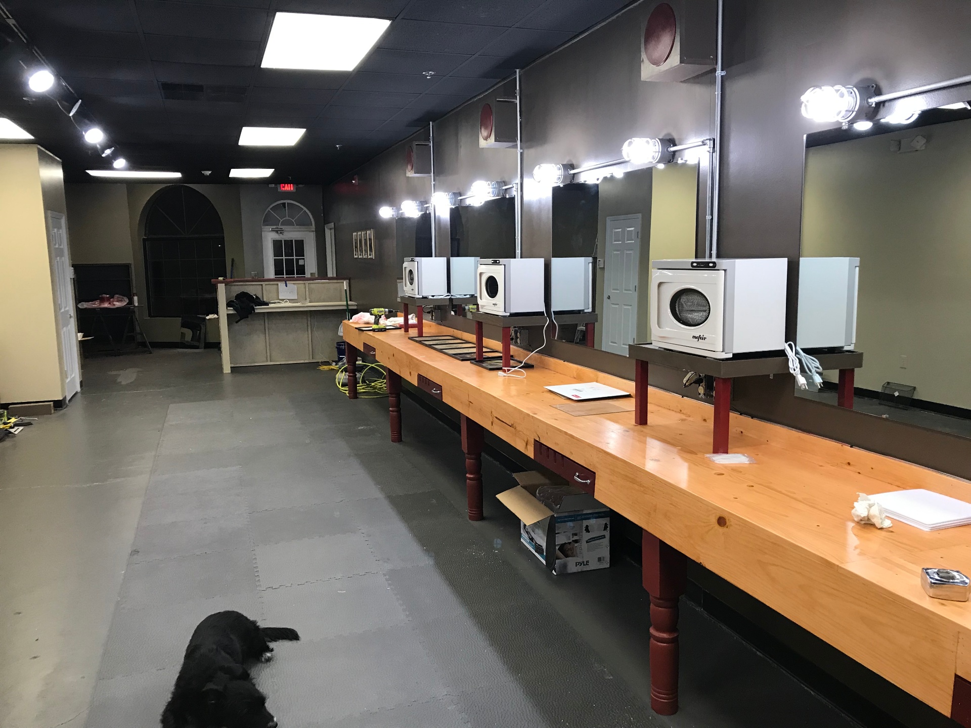 Completed barber shop with mounted dryers, lit mirrors, and finished styling stations