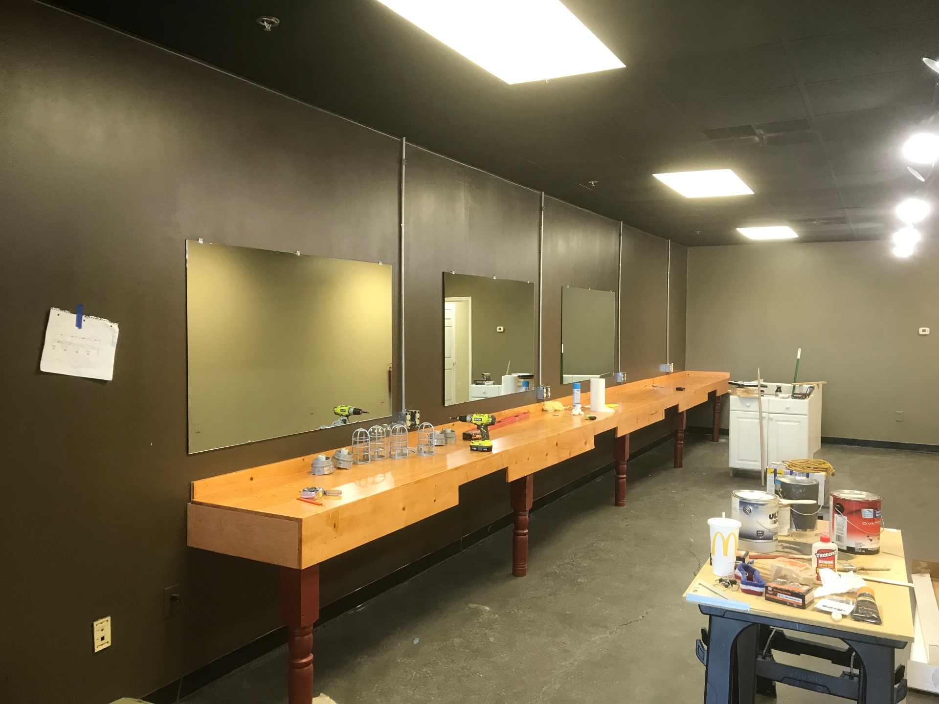 Barber station installation in progress with mirrors, finished wood counters, and lighting prep underway