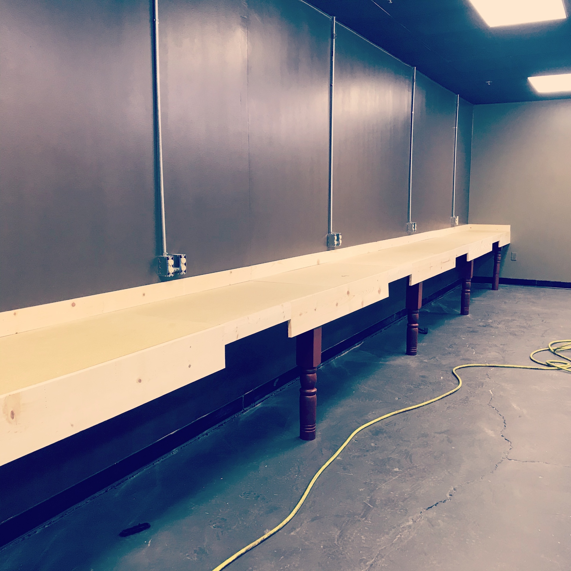 Early construction phase with freshly built long vanity frames and exposed electrical conduit