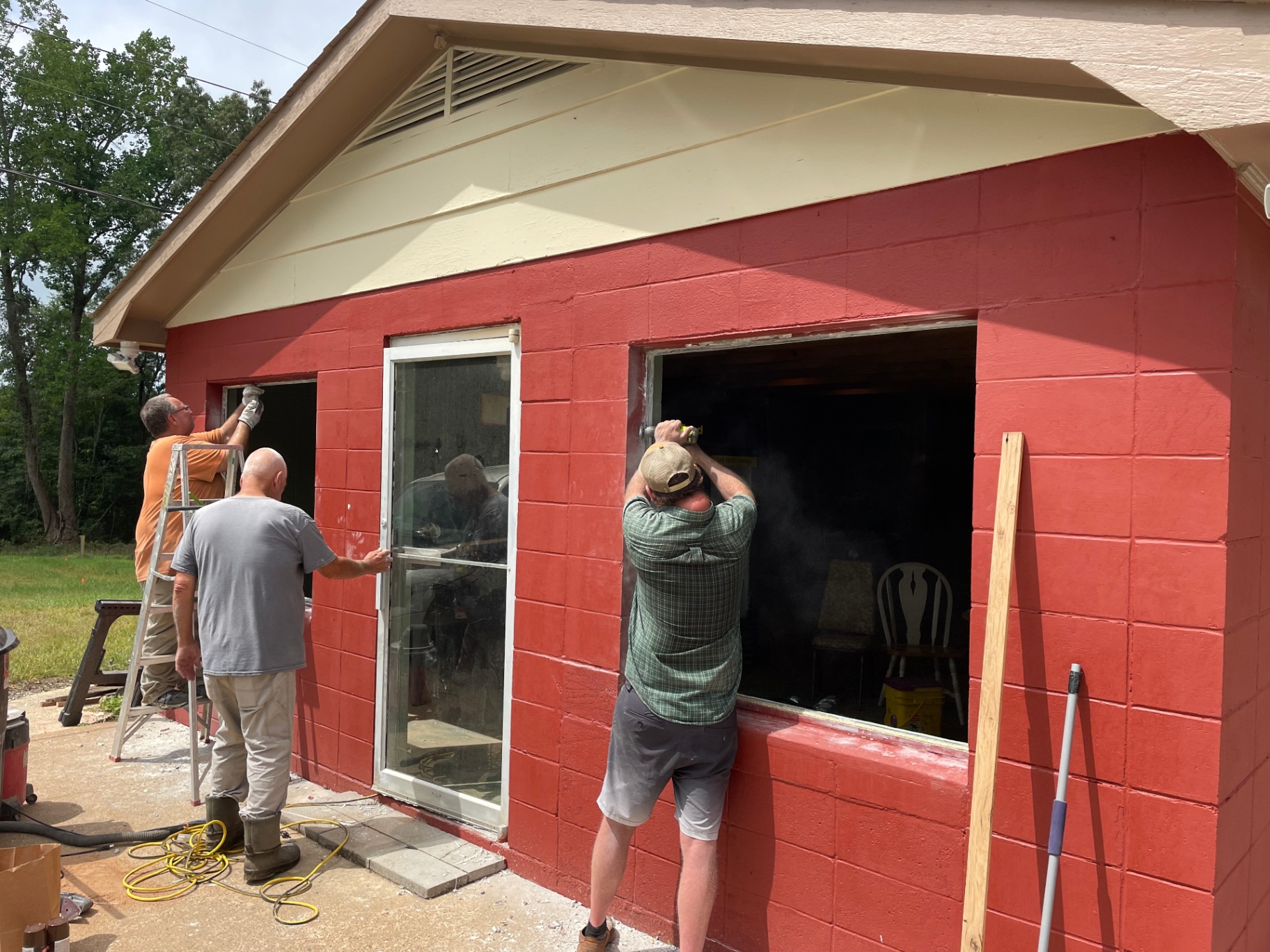 Crew installing new windows on the freshly painted red exterior