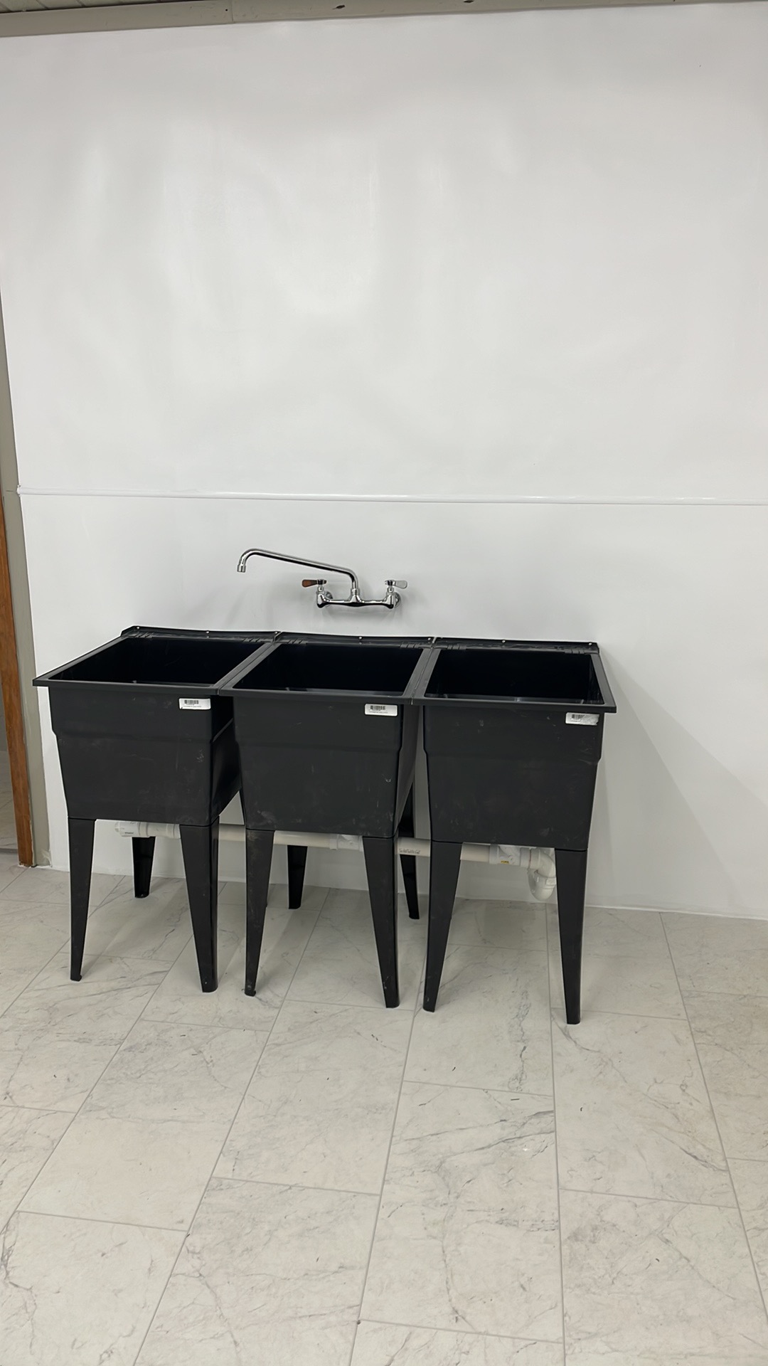 Triple-basin utility sink installed with wall-mounted faucet and new plumbing